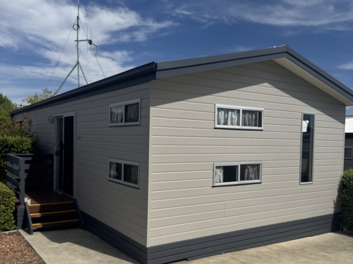 Freshly repainted holiday park cabin in warm white with navy trim